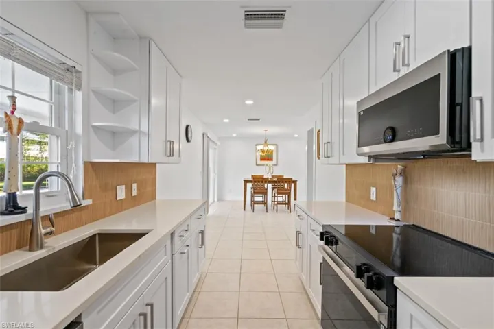 Kitchen with open shelves, stainless steel appliances, white cabinets, light tile patterned flooring, and pendant lighting