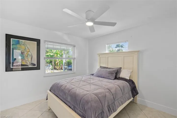 Bedroom with multiple windows, light tile patterned floors, and a ceiling fan