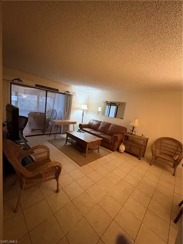 Neutral-toned tile flooring extends through the living area, featuring a sliding glass door providing access to an outdoor space