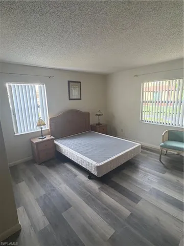 Spacious room featuring wood-finish flooring, light-colored walls, and two windows equipped with vertical blinds