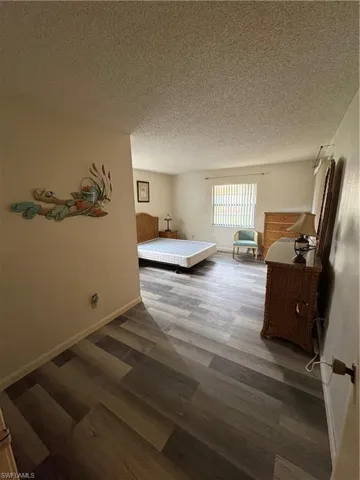 Spacious room featuring wood-finish flooring, a window with blinds, and neutral wall tones