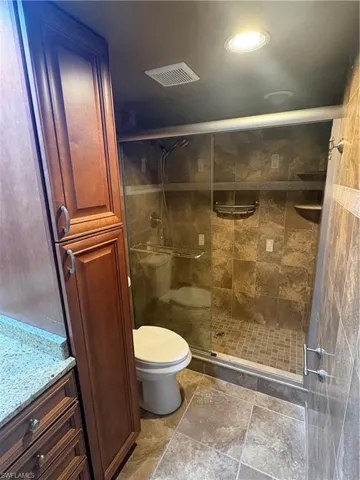 Walk-in shower with clear glass enclosure and stone-look tile walls