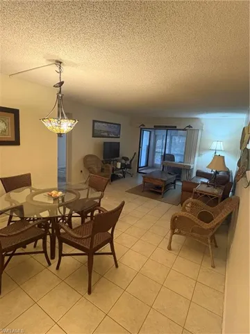 Open-concept living area featuring light-toned square tile flooring throughout