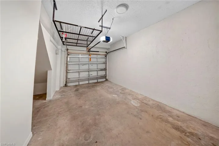 Garage featuring a concrete floor, built-in overhead storage rack, and an automatic garage door opener