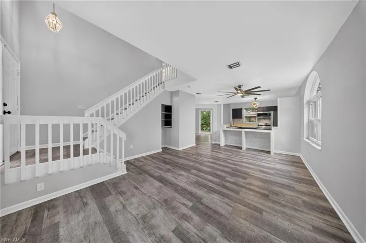 Expansive living area featuring wood-finish flooring, a contemporary ceiling fan, and an arched window
