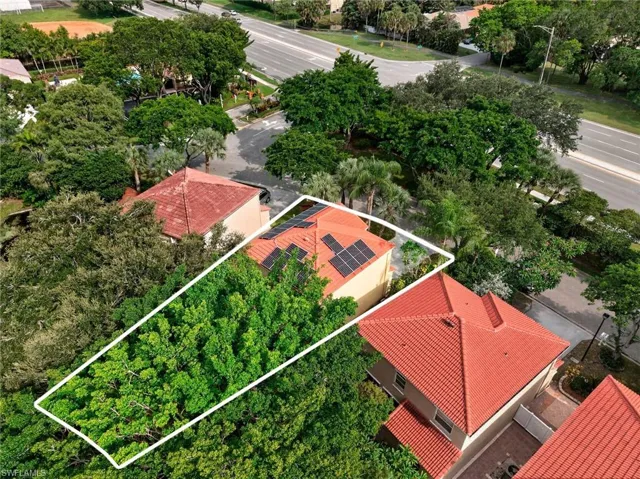 Property with solar panels on a red tile roof and mature trees