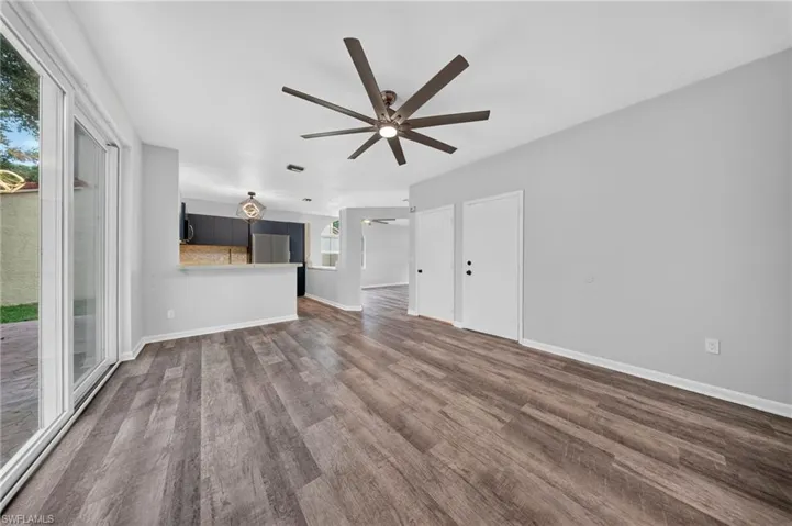 Spacious room featuring wood-finish flooring, a contemporary ceiling fan, and sliding glass doors