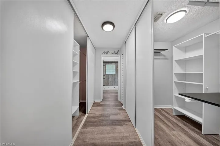 Hallway featuring wood-finish flooring, built-in shelving, and recessed ceiling lighting