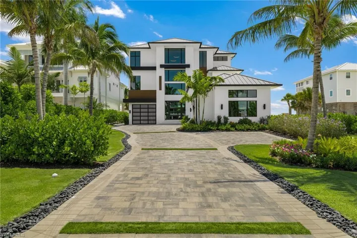 Contemporary residence featuring a multi-level design, white stucco exterior, black-framed windows, and a metal roof