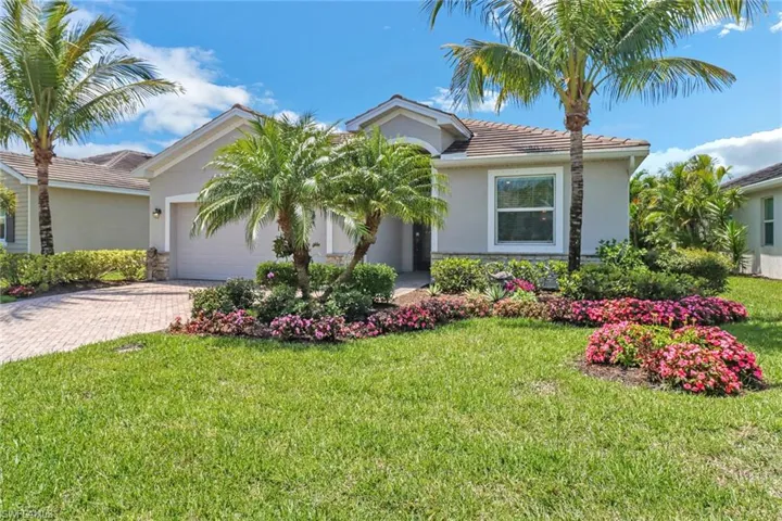 View of front facade featuring decorative driveway, a tiled roof, an attached garage, stucco siding, and a front lawn