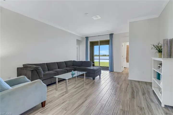 Living room with ornamental molding, light wood finished floors, and a water view