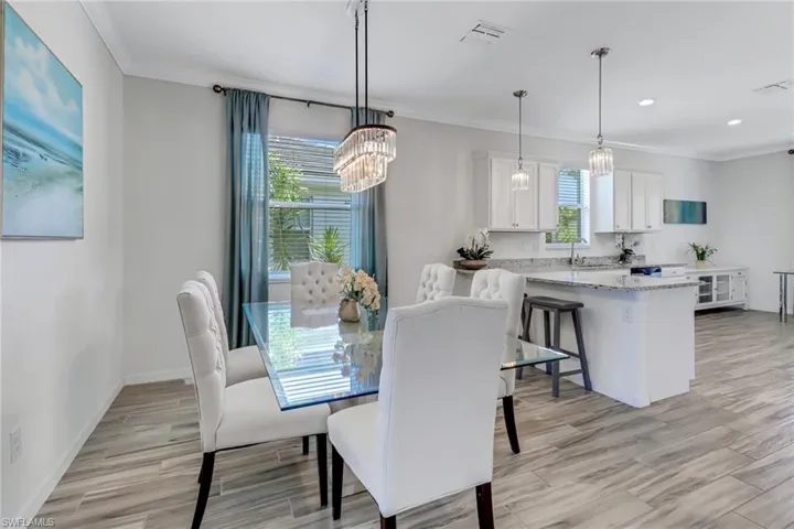Dining area featuring a chandelier, crown molding, light wood-style flooring, and recessed lighting