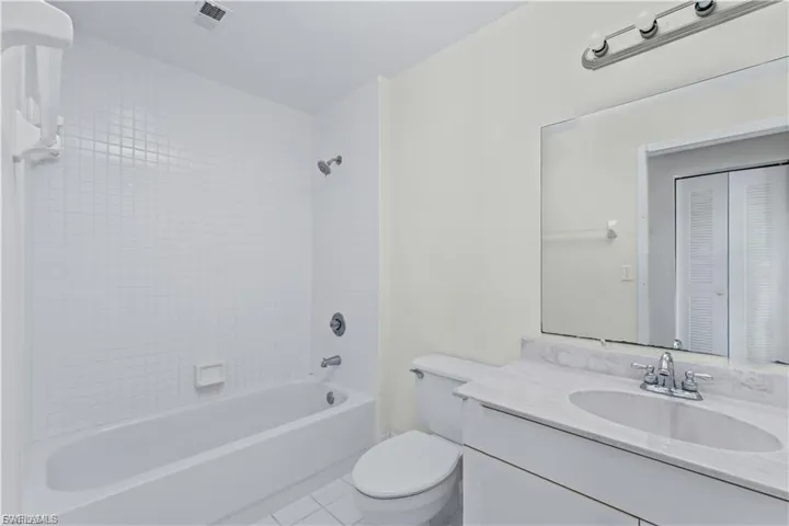 Bathroom featuring shower / bath combination, vanity, tile patterned flooring, and a closet