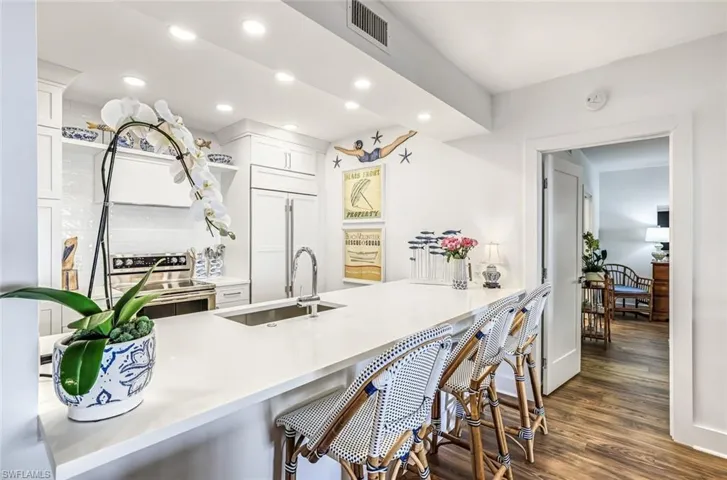 Kitchen with recessed lighting, electric stove, a peninsula, dark wood-style floors, and a breakfast bar