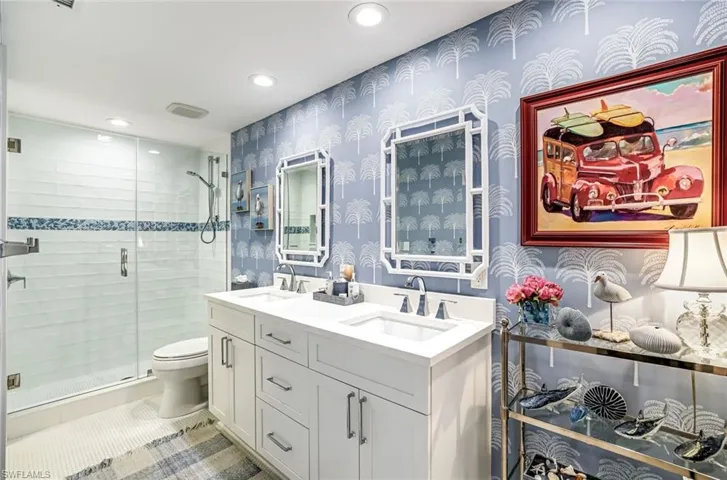 Bathroom featuring double vanity, recessed lighting, a stall shower, wallpapered walls, and light tile patterned flooring