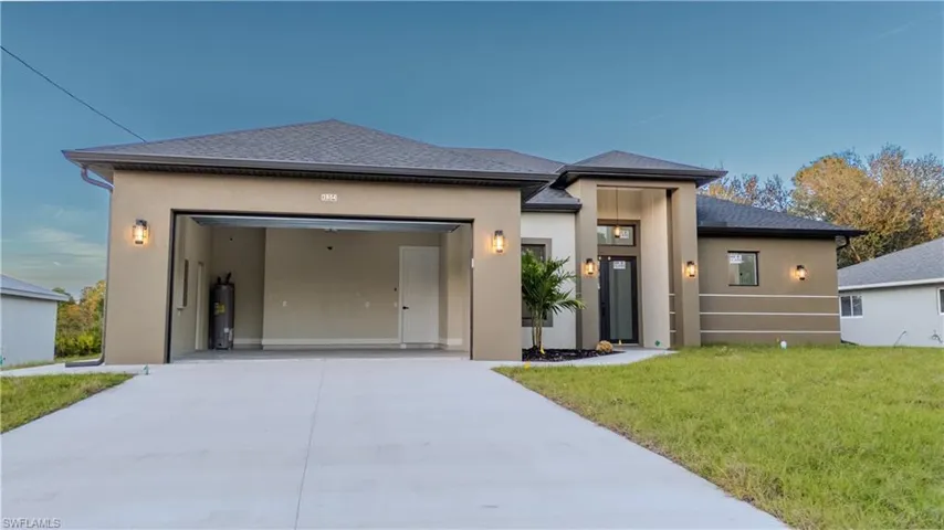 View of front facade featuring stucco siding, concrete driveway, and a front yard