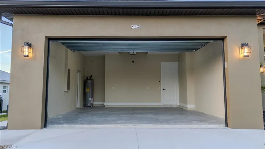 Garage featuring electric water heater and concrete driveway