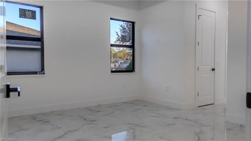 Empty room featuring light marble finish flooring and baseboards