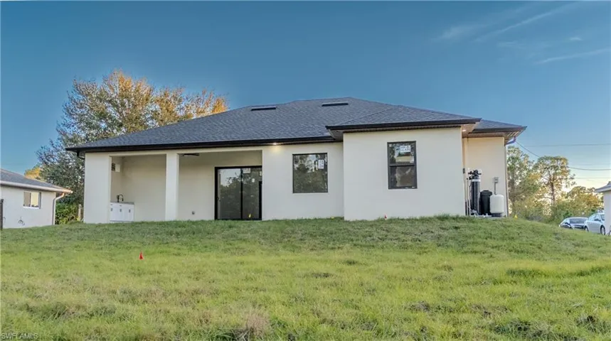 Rear view of house featuring stucco siding, a yard, a patio area, and a shingled roof
