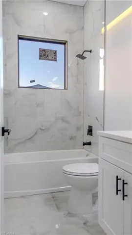Bathroom with shower / bath combination, vanity, and plenty of natural light