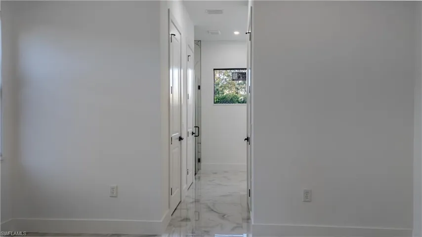 Hall featuring light marble finish floors and recessed lighting