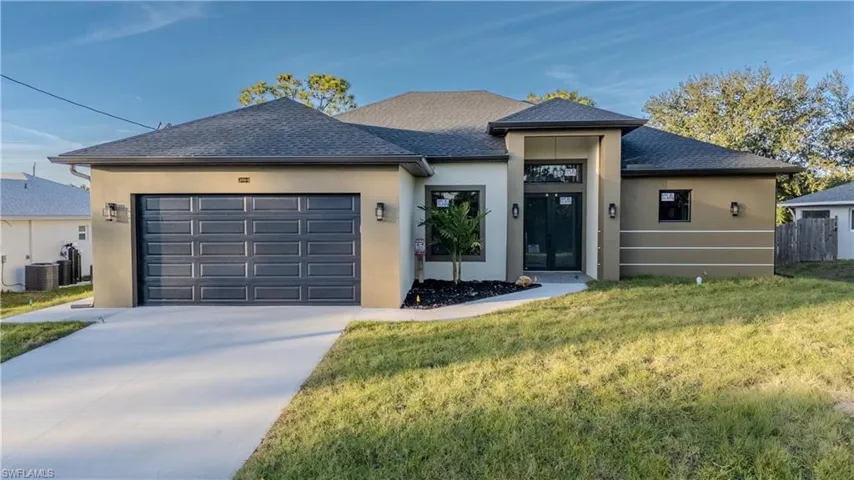 View of front facade with stucco siding, roof with shingles, concrete driveway, and a garage