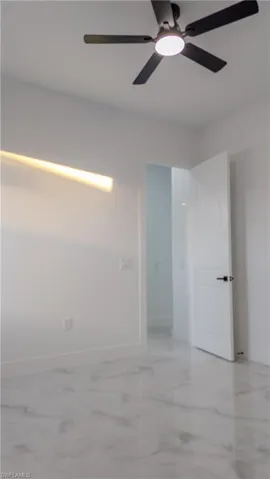 Empty room with light marble finish flooring and a ceiling fan