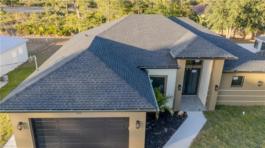 View of front of home with roof with shingles, stucco siding, a garage, and driveway