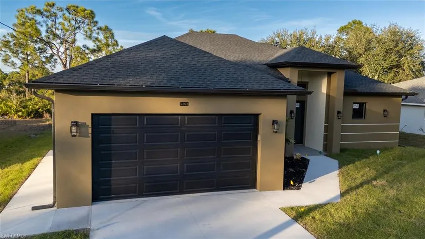 View of front of property featuring roof with shingles, stucco siding, concrete driveway, and a front lawn