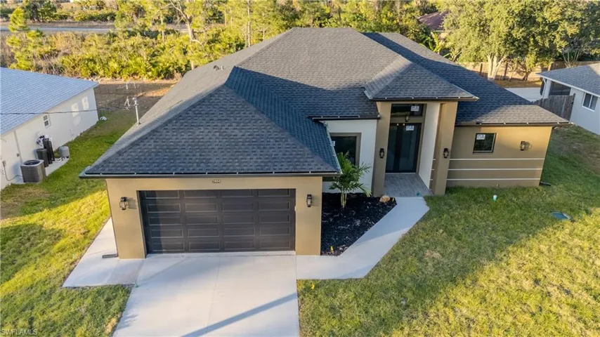 View of front facade featuring roof with shingles, stucco siding, and concrete driveway