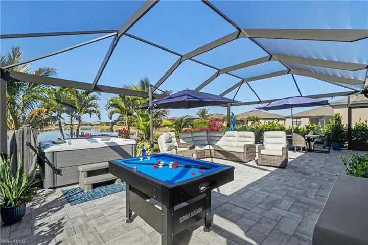 View of patio / terrace featuring glass enclosure, a hot tub, a sunroom, an outdoor lounge area, and a water view