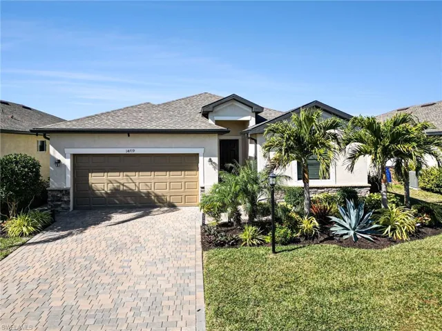 View of front of home with stucco siding, decorative driveway, a front yard, and an attached garage