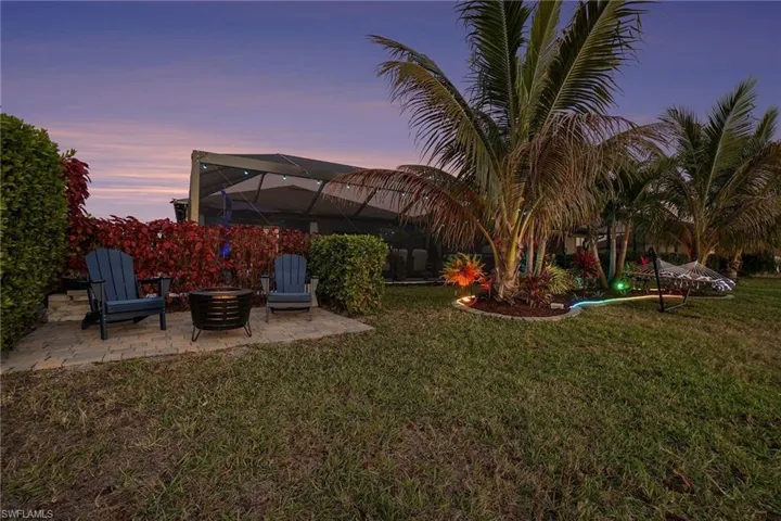 Yard at dusk featuring glass enclosure, a yard, and a patio area