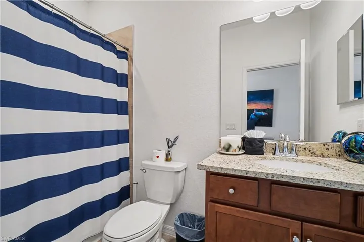 Full bath with a textured wall, a shower with curtain, and vanity