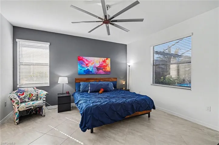 Tiled bedroom featuring a ceiling fan and baseboards