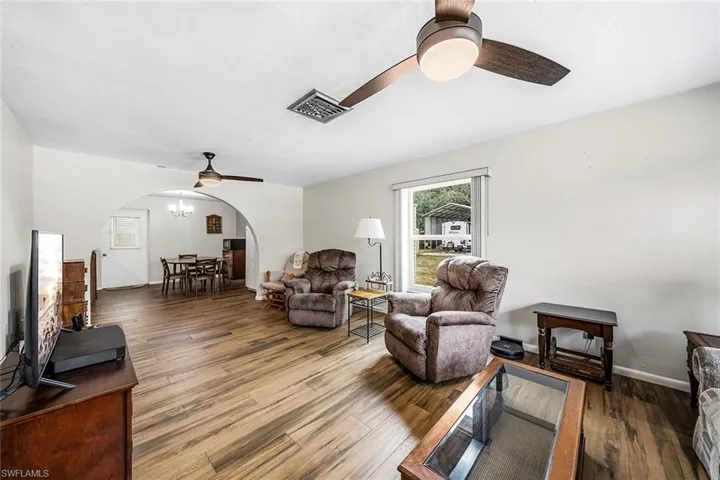 Living area with wood finished floors, arched walkways, ceiling fan, and a chandelier