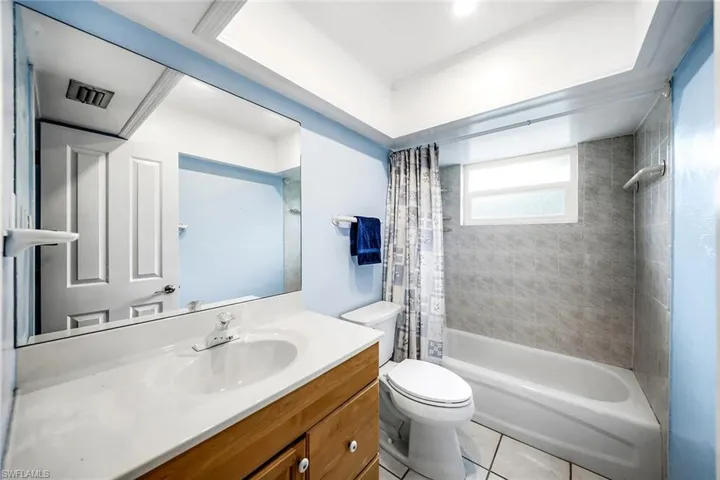 Full bathroom with shower / bath combination with curtain, vanity, and light tile patterned flooring