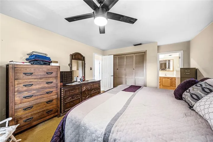 Bedroom featuring light carpet, a closet, a ceiling fan, and connected bathroom