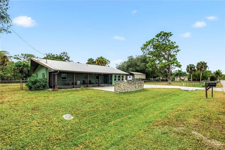 View of front of property with a sunroom, driveway, and a metal roof
