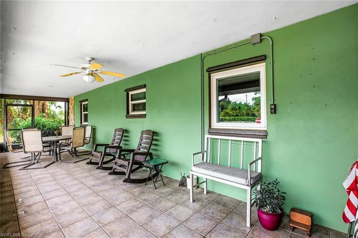View of patio featuring a sunroom, a ceiling fan, and outdoor dining area