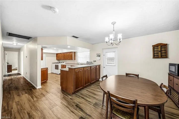 Kitchen with light countertops, a peninsula, a chandelier, hanging light fixtures, and brown cabinets