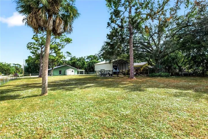 View of yard with a carport and view of wooded area