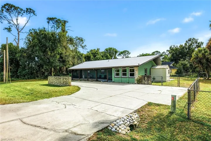 View of front facade featuring concrete driveway and a metal roof