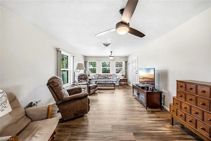 Living area with dark wood-style flooring and a ceiling fan