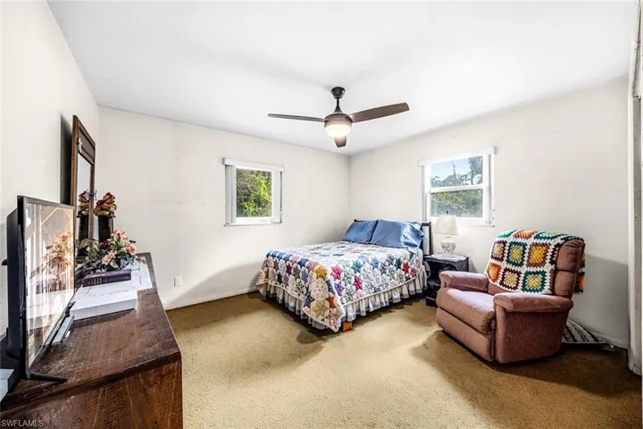 Carpeted bedroom with multiple windows and a ceiling fan
