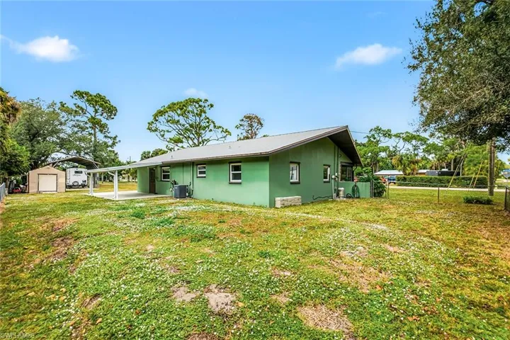 Back of property with stucco siding, a patio area, a carport, and a storage shed