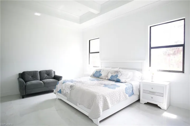 Tiled bedroom featuring beamed ceiling and multiple windows