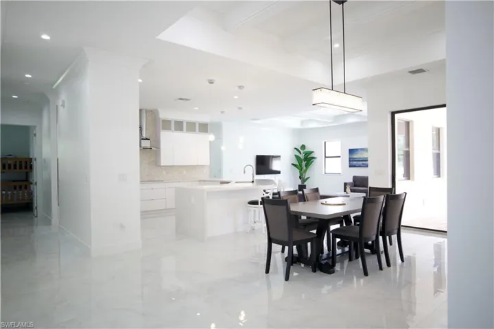 Dining space featuring beamed ceiling, sink, coffered ceiling, and light tile floors