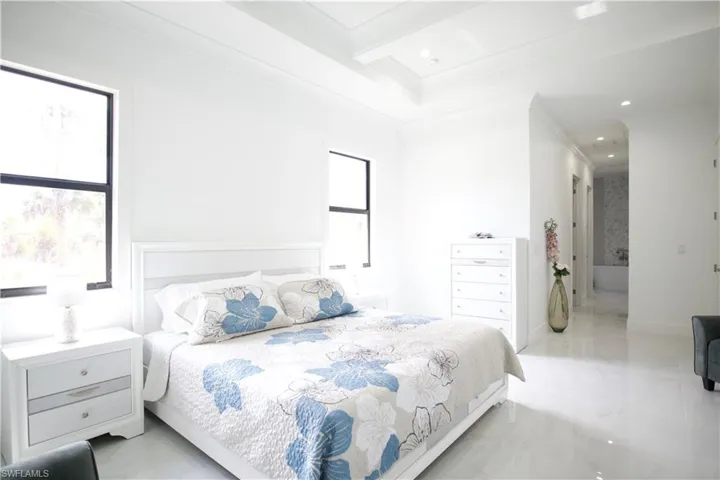 Bedroom with beam ceiling, crown molding, and light tile floors