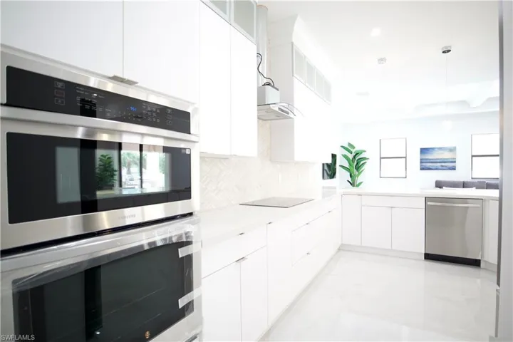 Kitchen featuring appliances with stainless steel finishes, white cabinets, decorative light fixtures, backsplash, and light tile flooring
